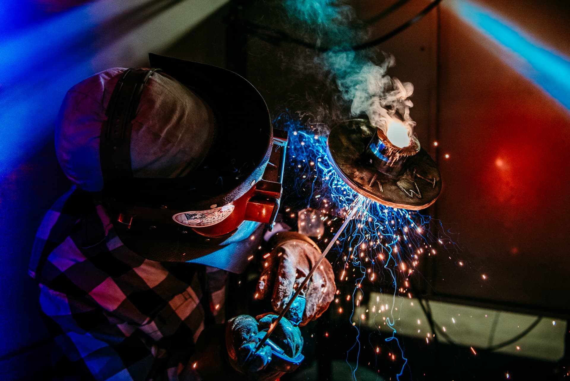 A KWI welder under the hood with blue and orange sparks flying off the arc